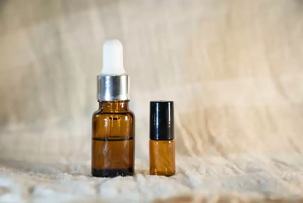 Two beard oil bottles standing next to each other against a tan background