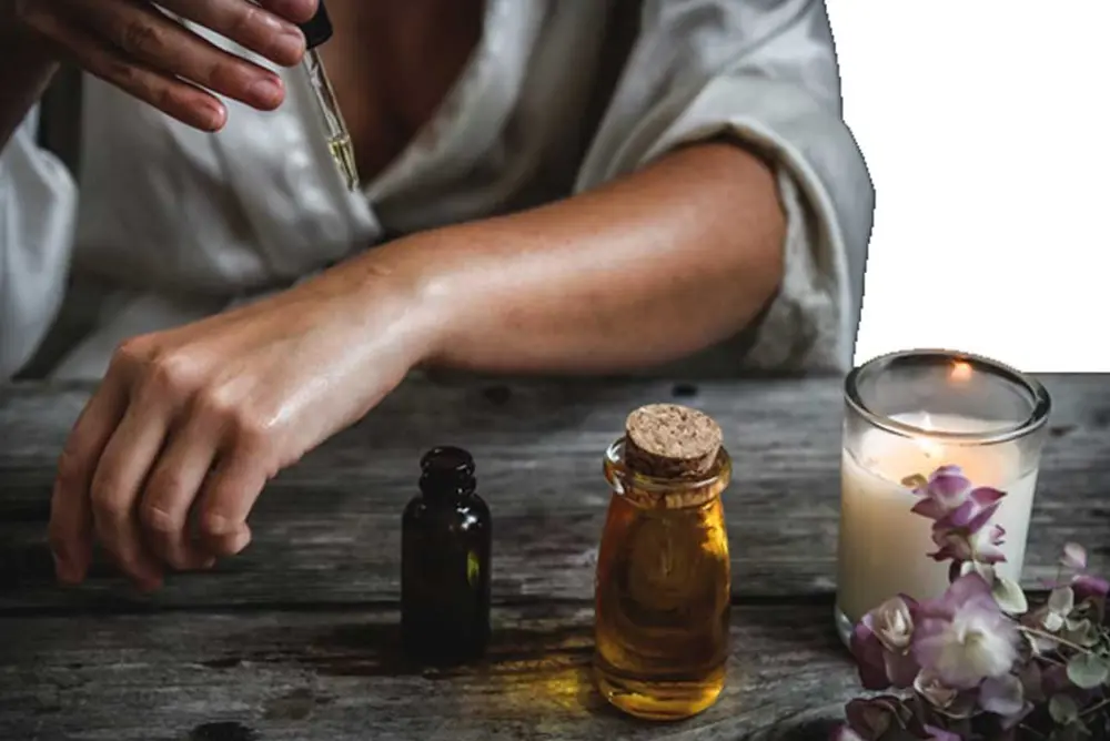 person sitting at a desk dropping essential oil onto their skin